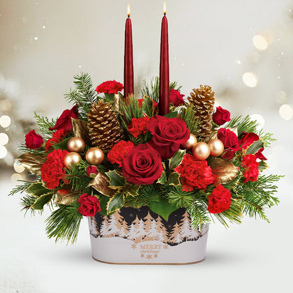Decorative floral arrangement with red roses, gold pinecones, and candles on a white background.