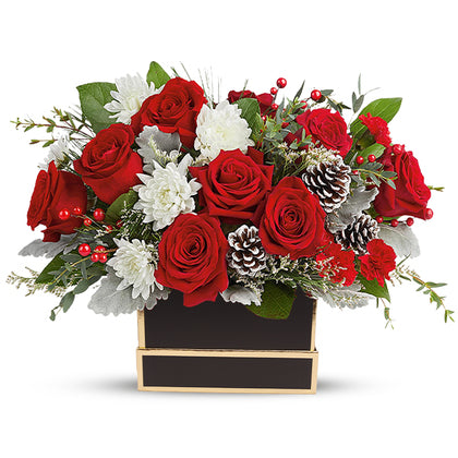 Floral arrangement with red roses, white flowers, and pinecones in a black box on a white background
