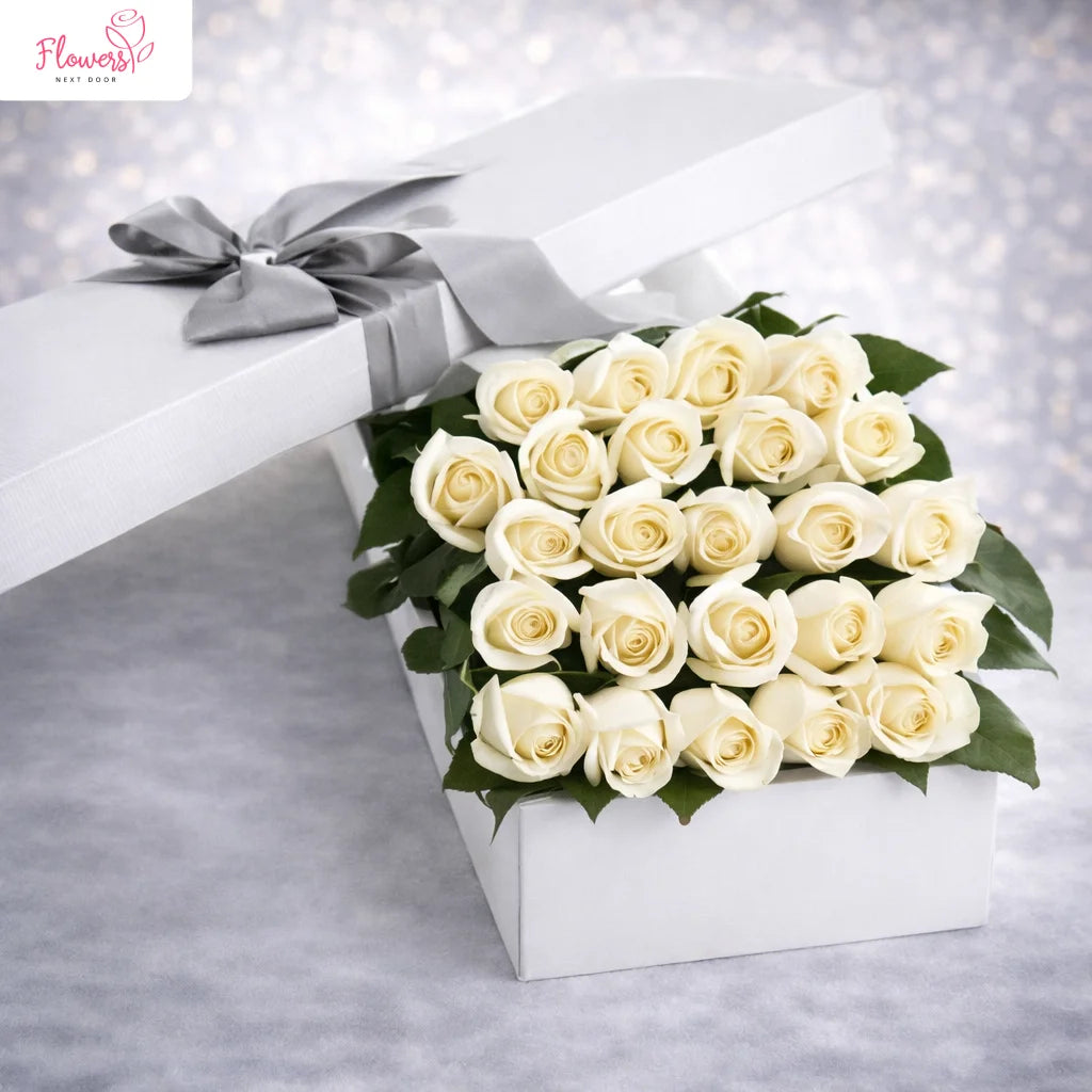White roses in a box with a silver bow on a gray background