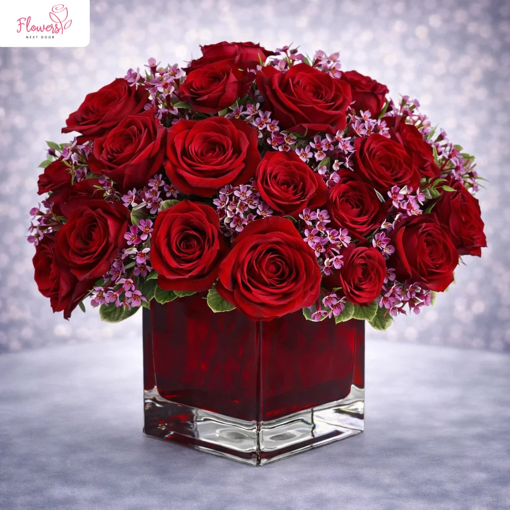 bunch of red roses in a glass vase by flower next door