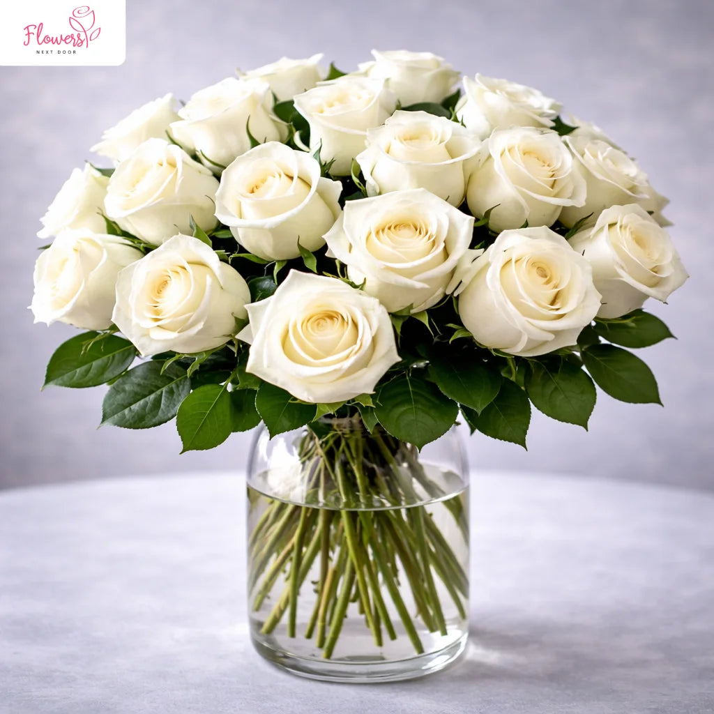 Bouquet of white roses in a clear vase on a gray background